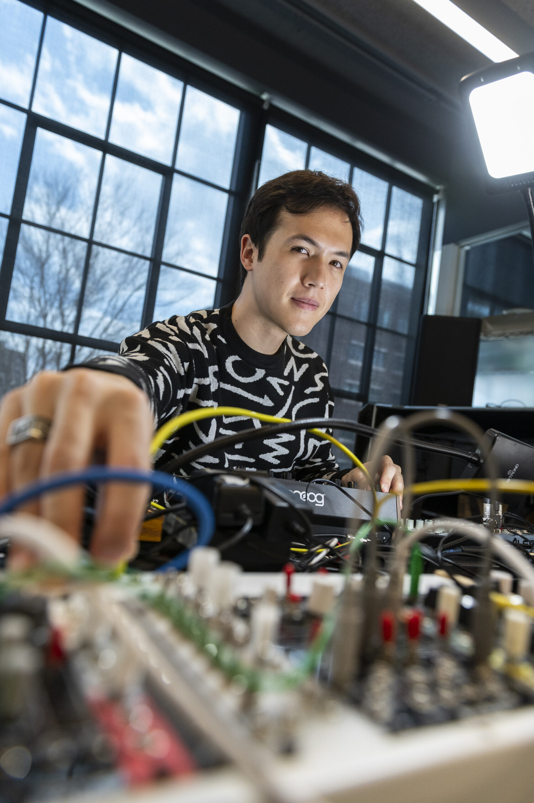 Man adjusting electronic music equipment in a studio setting