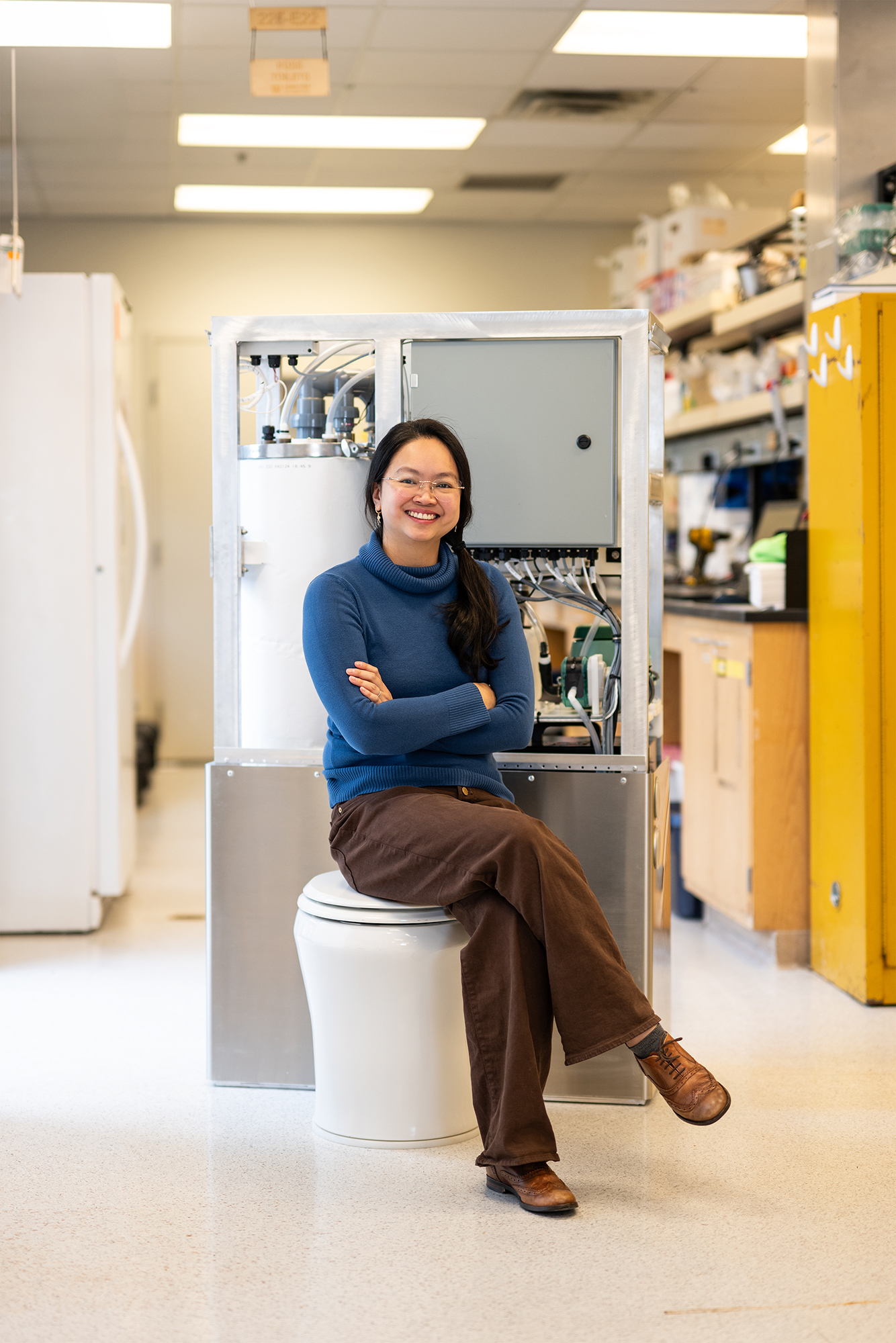 Smiling woman in laboratory sitting on a modern white toilet